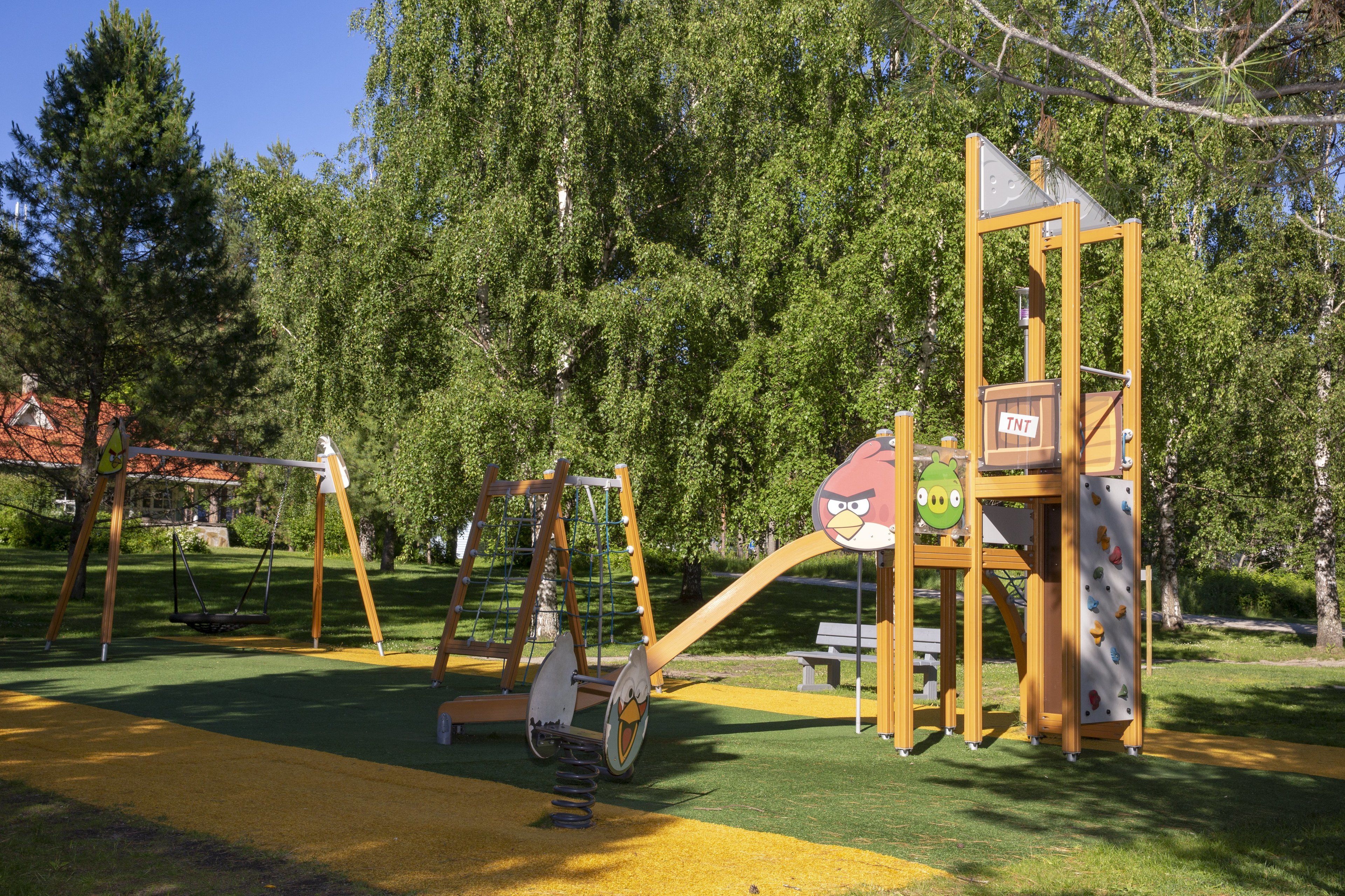 A playground with swings, a climbing structure, and a slide.