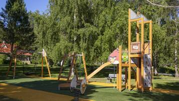 A playground with swings, a climbing structure, and a slide.