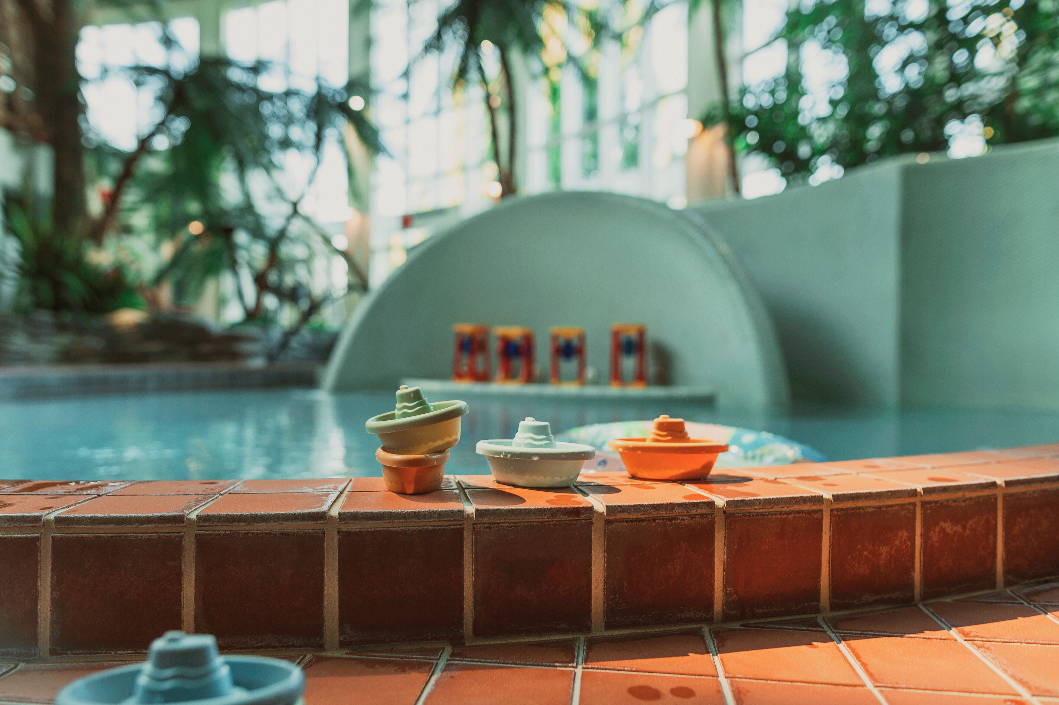 A poolside area with tiled flooring, a pool, and a few decorative items.