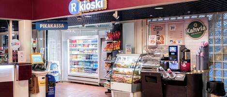 A R Kioski store with a refrigerated display, a coffee machine, and a variety of packaged goods.