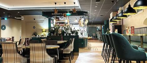 A modern cafe interior with a central bar area, seating arrangements, and a ceiling with recessed lighting.