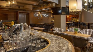 A bar area with a counter, stools, and a seating area with a 'COTTON' sign.