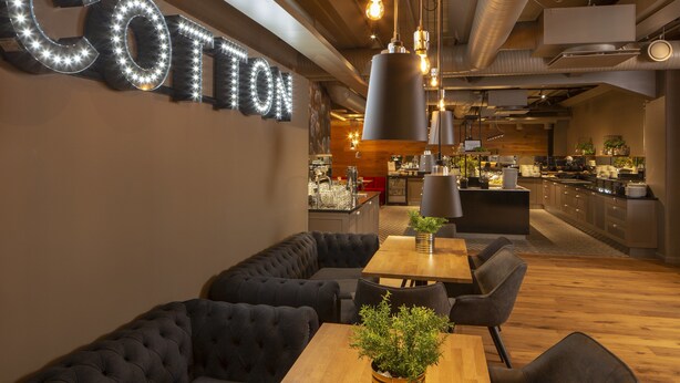A modern interior with a seating area, a bar, and a kitchen visible in the background.