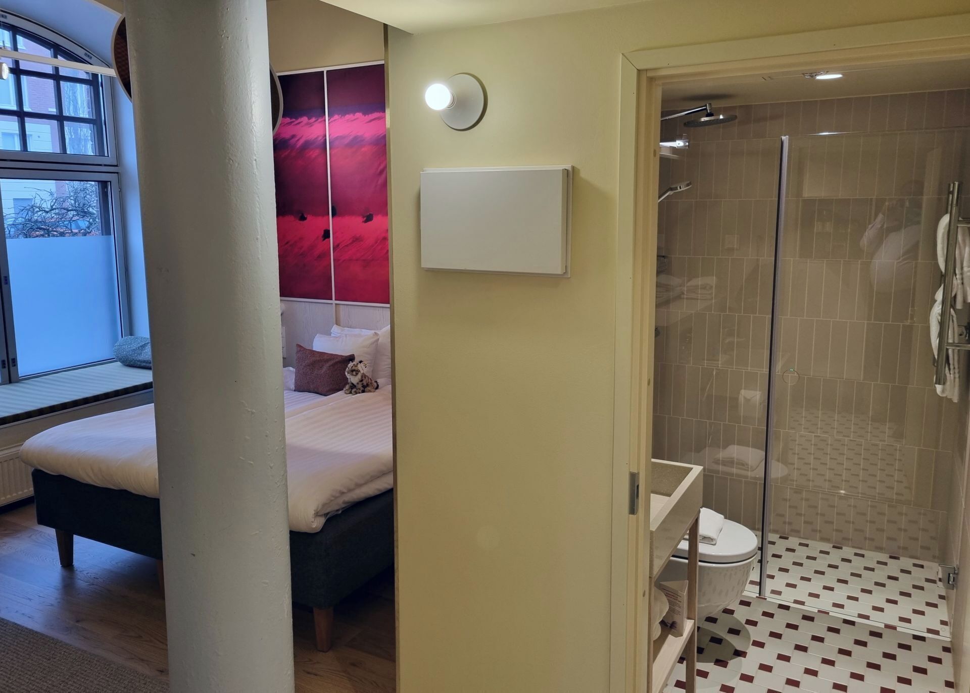A bedroom with a bed, a bedside table, and a window.