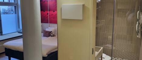 A bedroom with a bed, a bedside table, and a window.