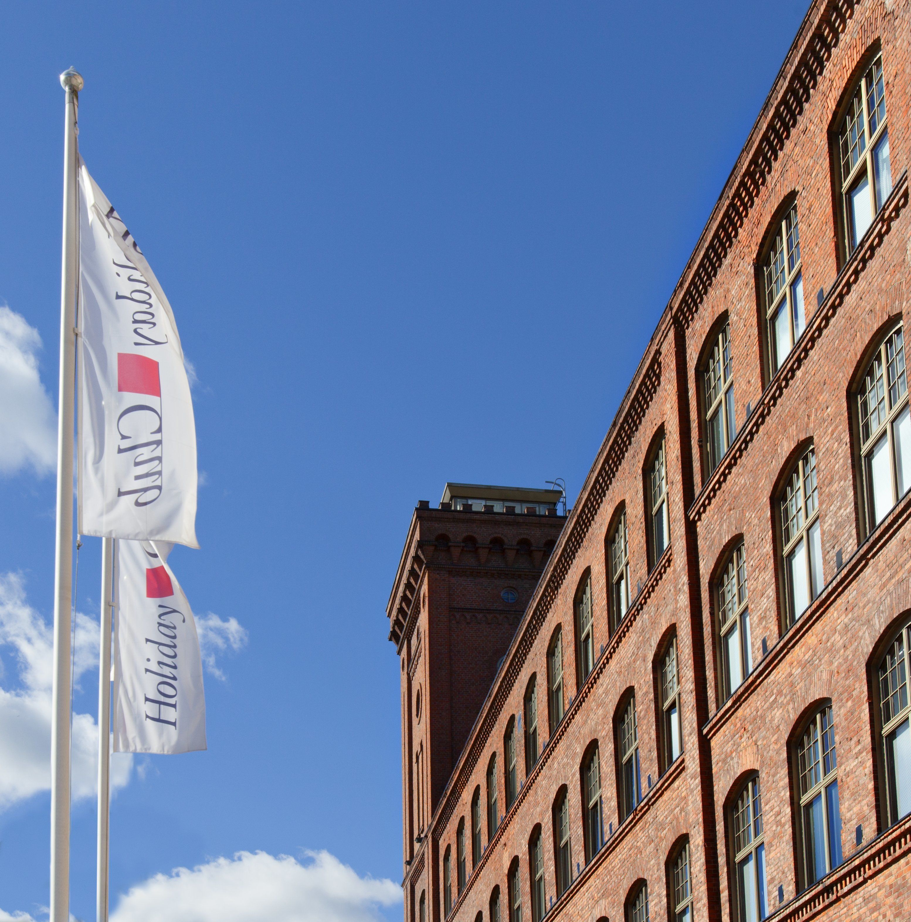 A red brick building with multiple windows and a flagpole with flags.