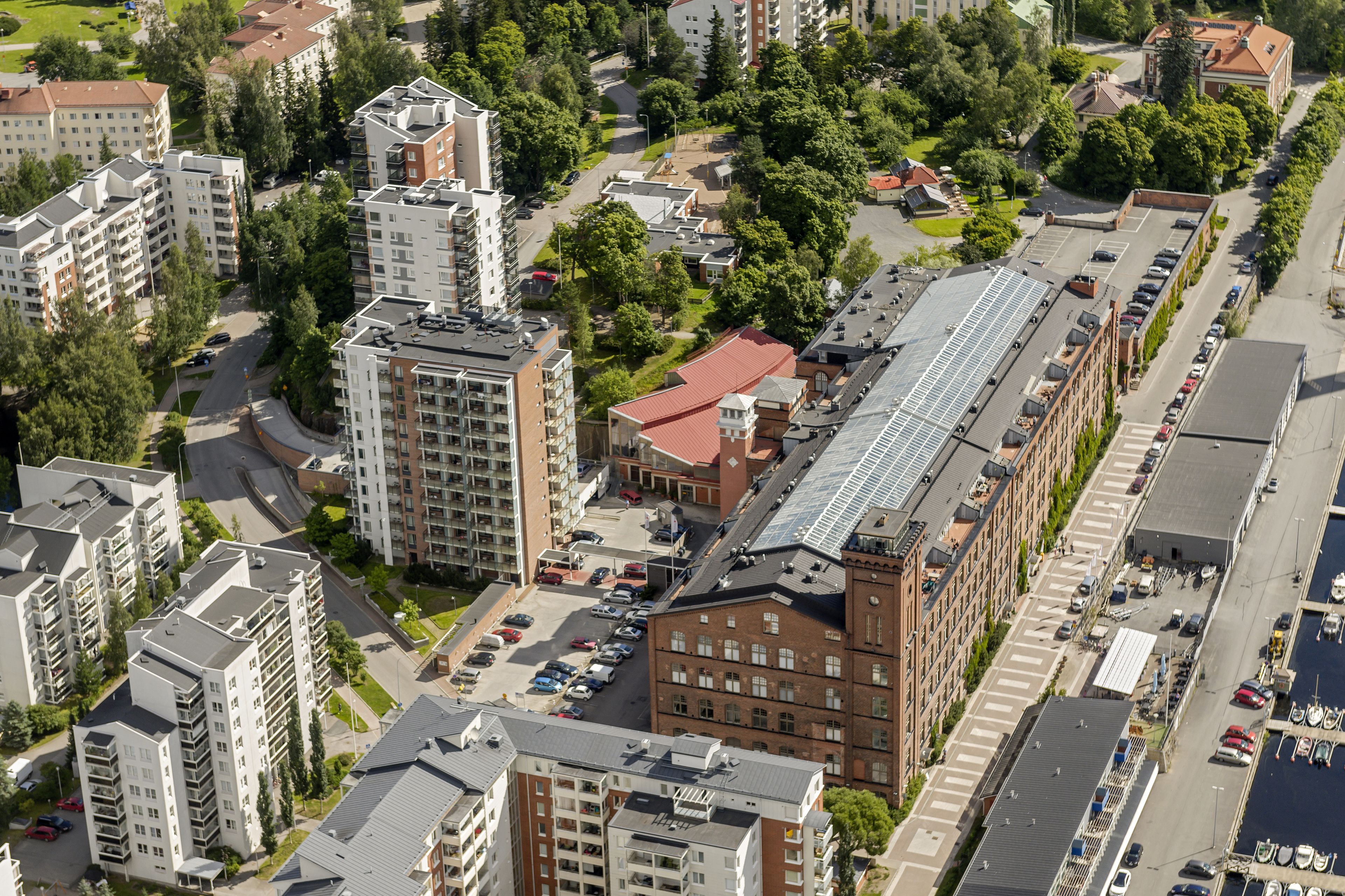 Ilmakuva asuinalueesta, jossa on useita kerrostaloja, parkkipaikka ja venesatama.