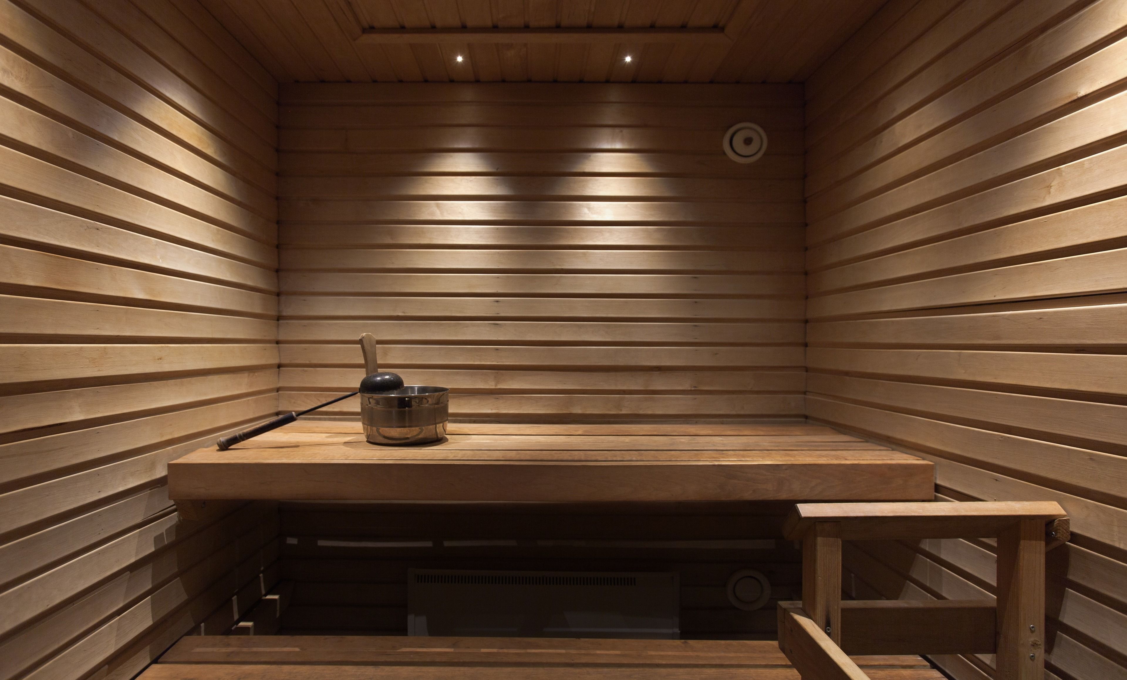Una sauna con listones de madera, un banco y una pequeña mesa con un cuenco y una cuchara.