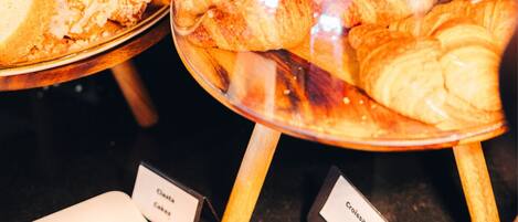 Una vitrina con varias opciones de repostería, incluyendo cruasanes y una tarta en porciones.