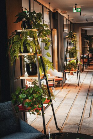 Un pasillo con varios puestos de plantas, una silla blanca y un sofá azul.
