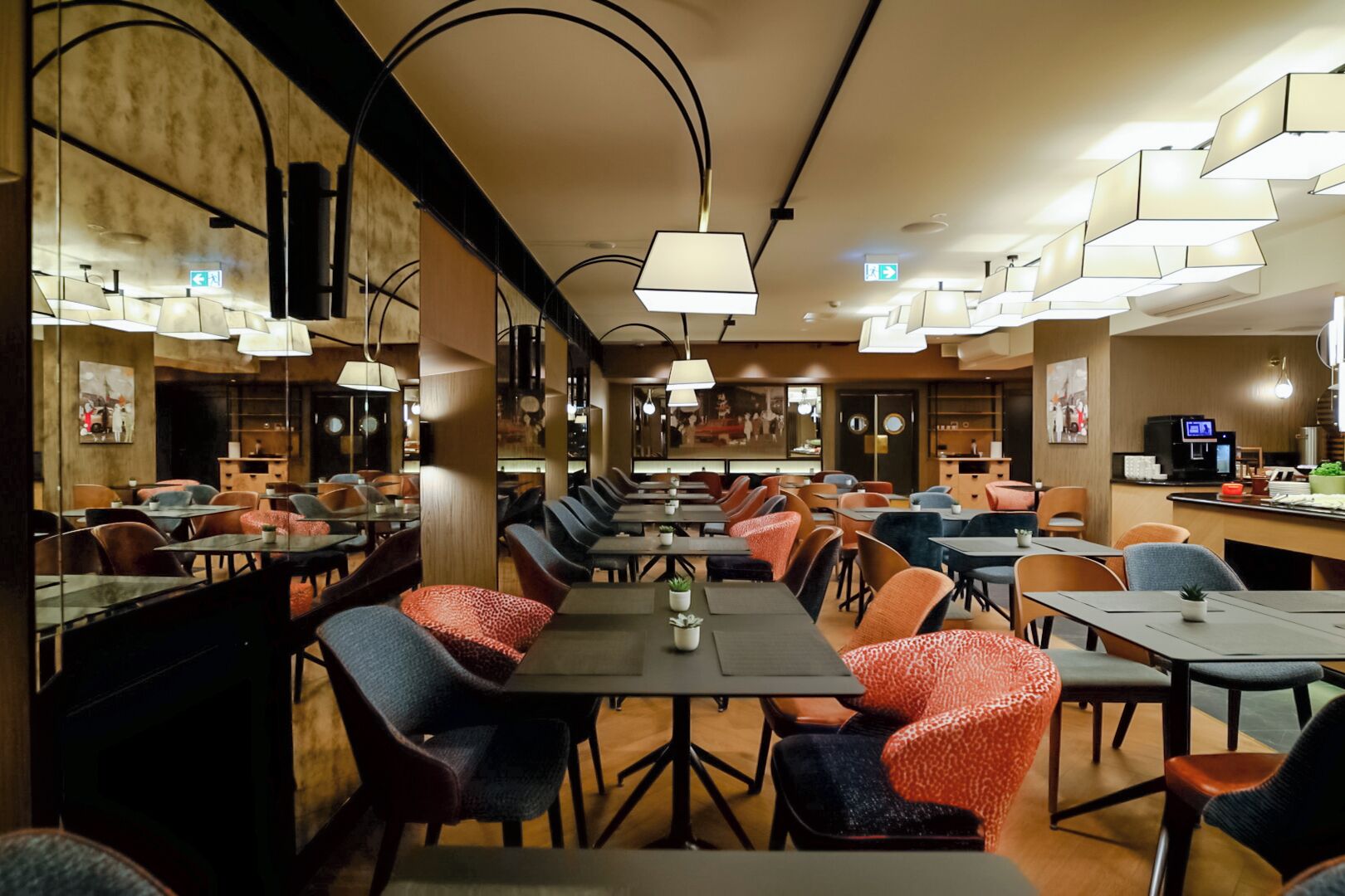 Un restaurante moderno con mesas comunitarias largas y cabinas individuales, que presenta iluminación colgante y una paleta de colores neutros.
