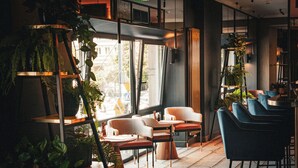 Un interior moderno con una zona de bar, asientos y plantas de interior.