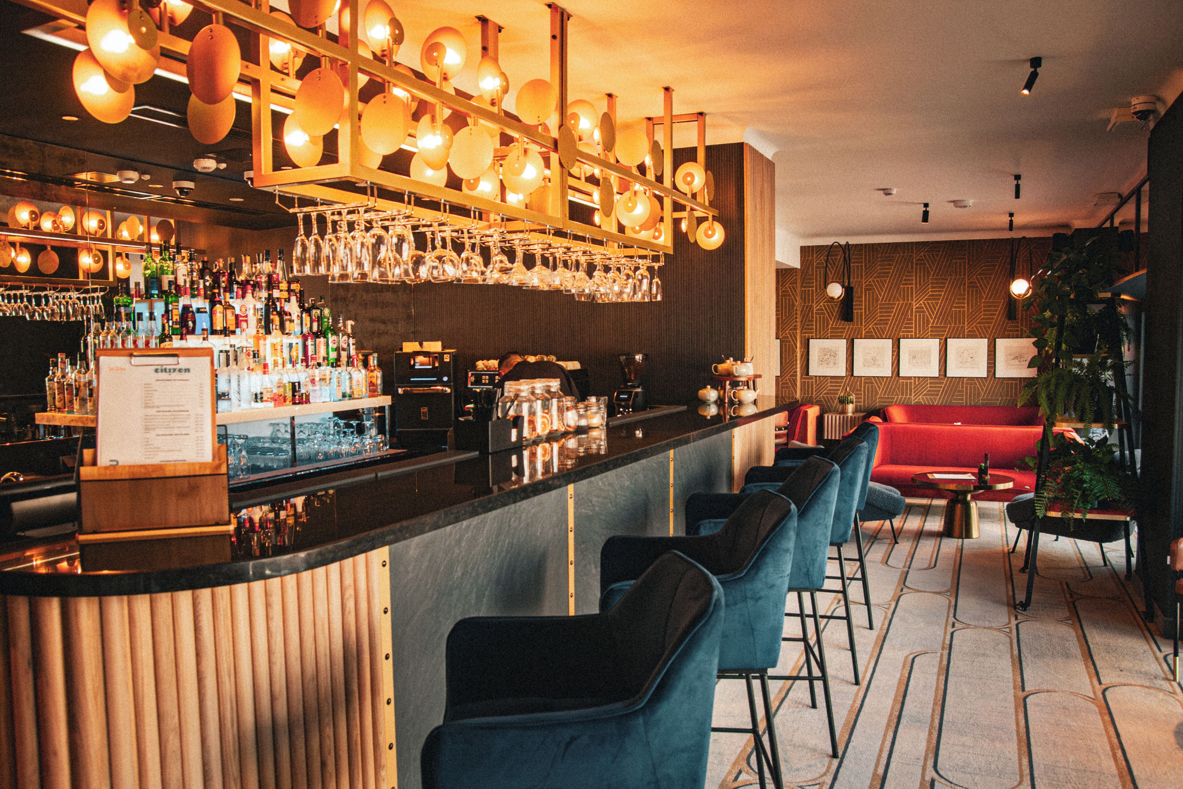 A bar area with a counter, bar stools, and a variety of bottles and glasses.