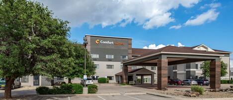 Un hôtel Comfort Suites doté d’un parking couvert et d’un bâtiment avec une enseigne.