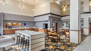 Eine moderne Hotelhalle mit einer zentralen Bar, Sitzgelegenheiten und einem gemusterten Teppich.