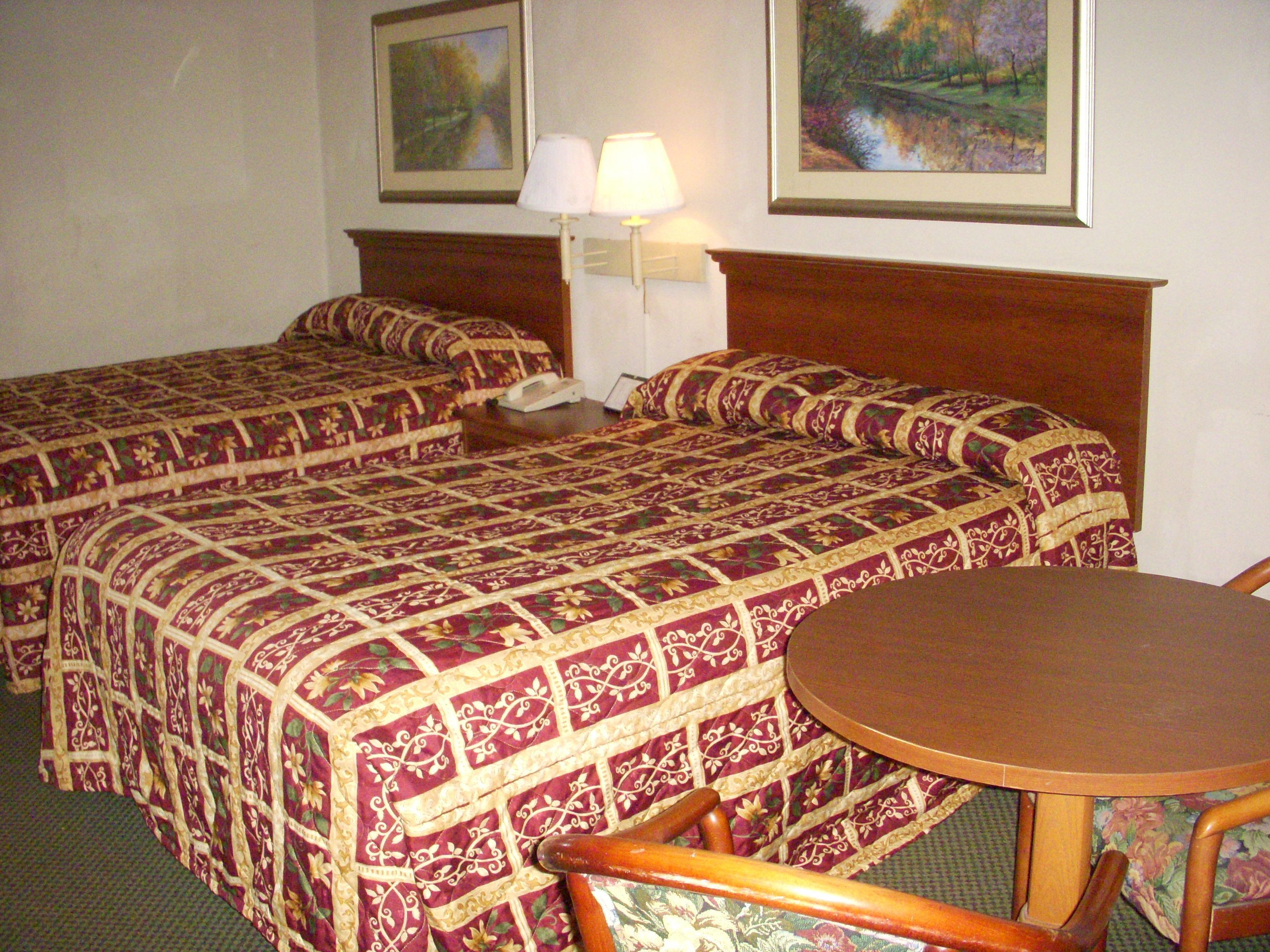 Een hotelkamer met twee bedden, een tafel en twee stoelen.
