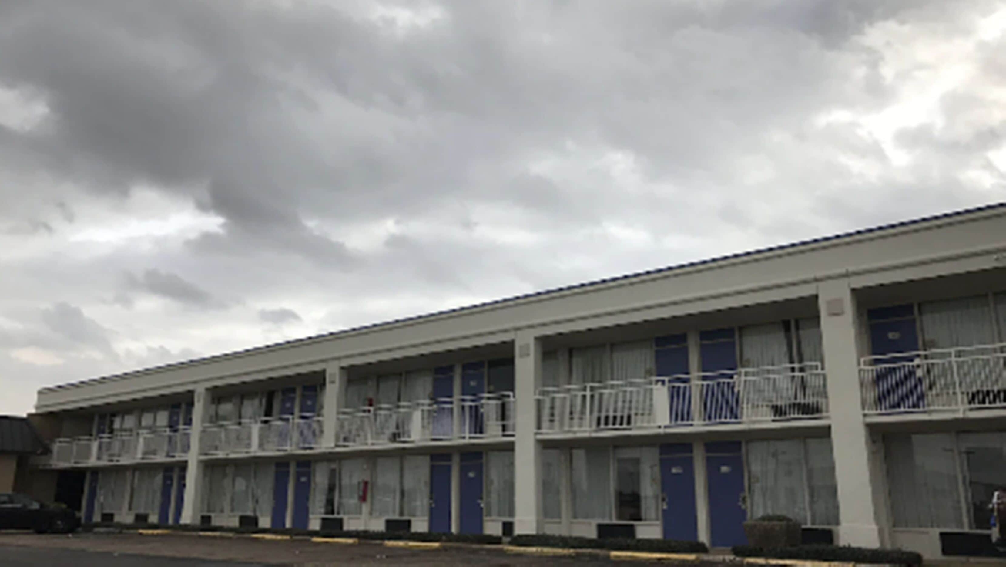 Una hilera de edificios tipo motel de una sola planta, con puertas azules y barandillas blancas en los balcones.