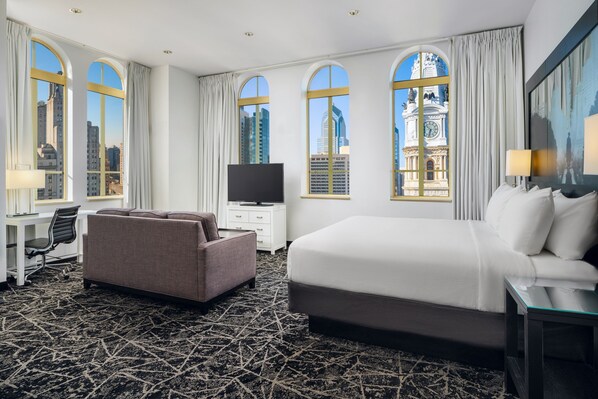 Relax in this stylish room with a large bed, sofa, and desk, offering city views from the large windows.