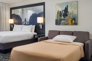Two beds, a large mirror, and a painting adorn this stylish room.