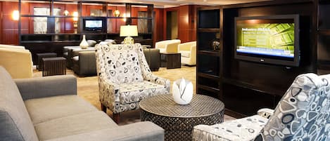 A modern hotel lobby with a TV displaying industry data, comfortable seating, and a well-lit ambiance.