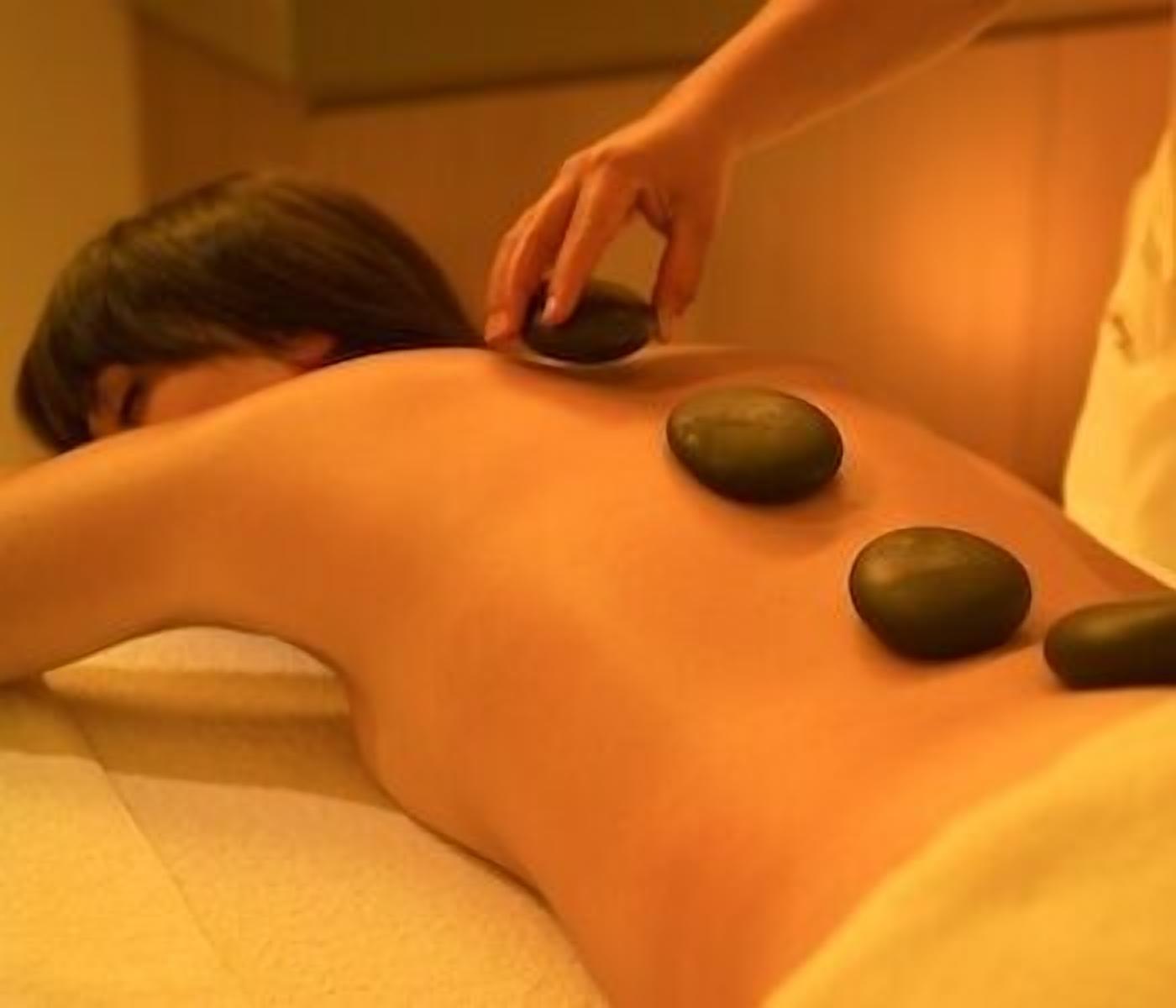 A person receiving a back massage with heated stones.