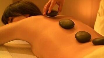 A person receiving a back massage with heated stones.