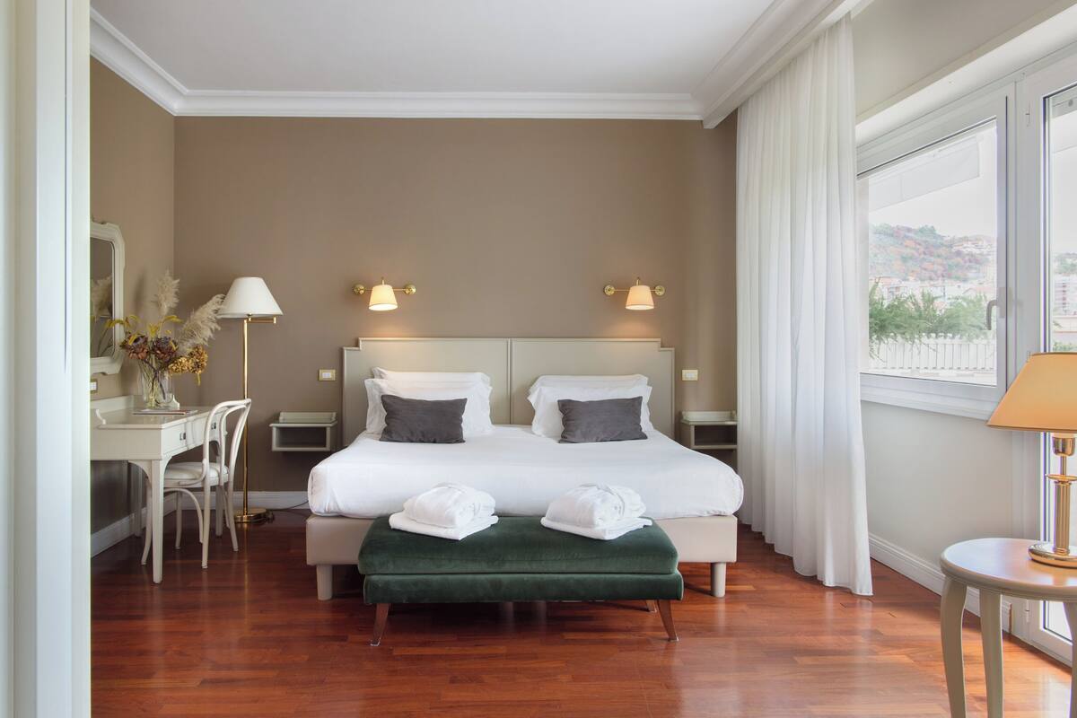 Habitación de hotel con una cama grande, dos mesitas de noche, un escritorio y una silla.