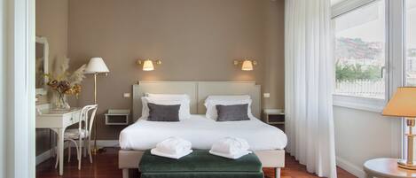 Habitación de hotel con una cama grande, dos mesitas de noche, un escritorio y una silla.