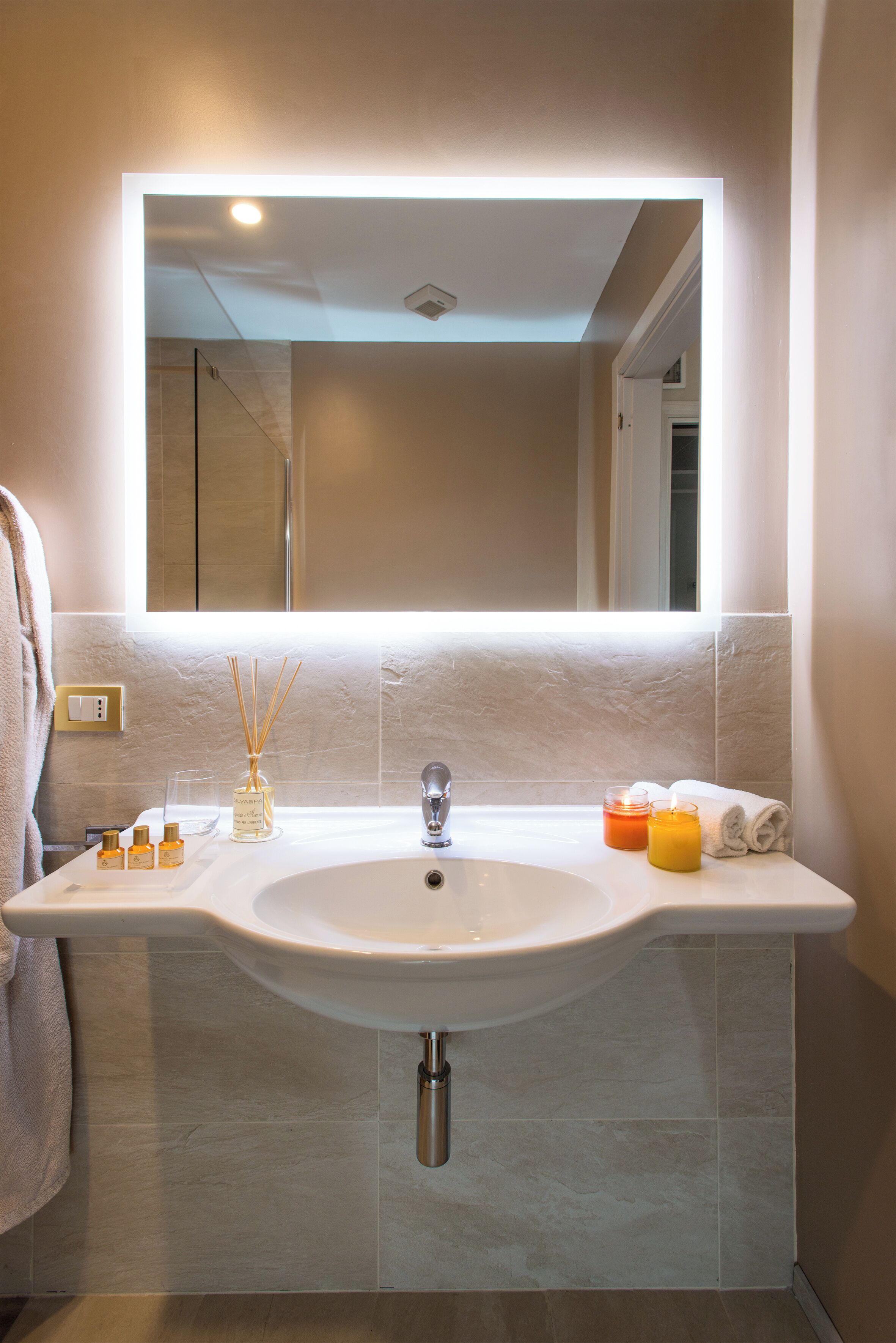 Un bagno con un ampio specchio, un lavandino bianco e un porta asciugamani.