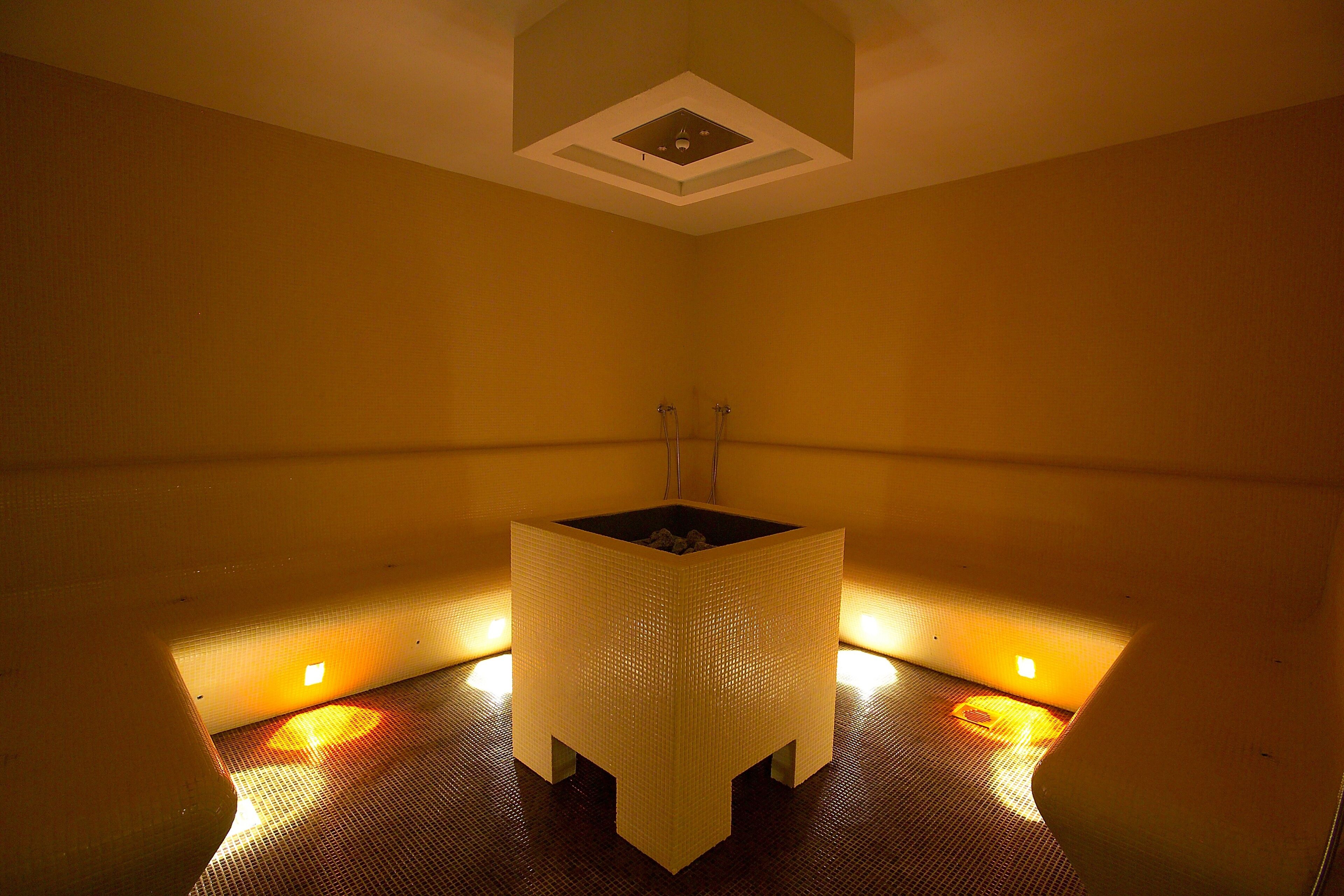 A small, square-shaped room with a central sink and two wall-mounted heaters.