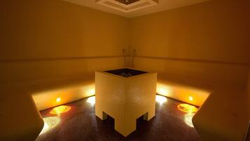 A small, square-shaped room with a central sink and two wall-mounted heaters.