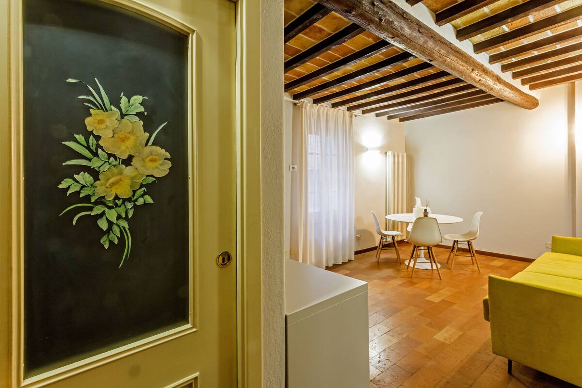 Una habitación con techo de madera, un comedor con mesa y sillas, y un sofá amarillo.