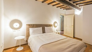 A bedroom with a large bed, two bedside tables, and a door leading to another room.