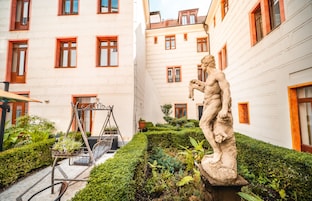 Um pátio com uma estátua, balanço e um edifício com janelas emolduradas a vermelho.