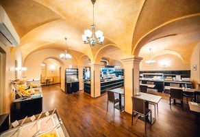 Uma sala de jantar espaçosa com pé direito alto, nichos em arco e um buffet com diversas opções de comida.