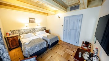 A hotel room with two beds, a wooden floor, a TV, and a desk with a chair.