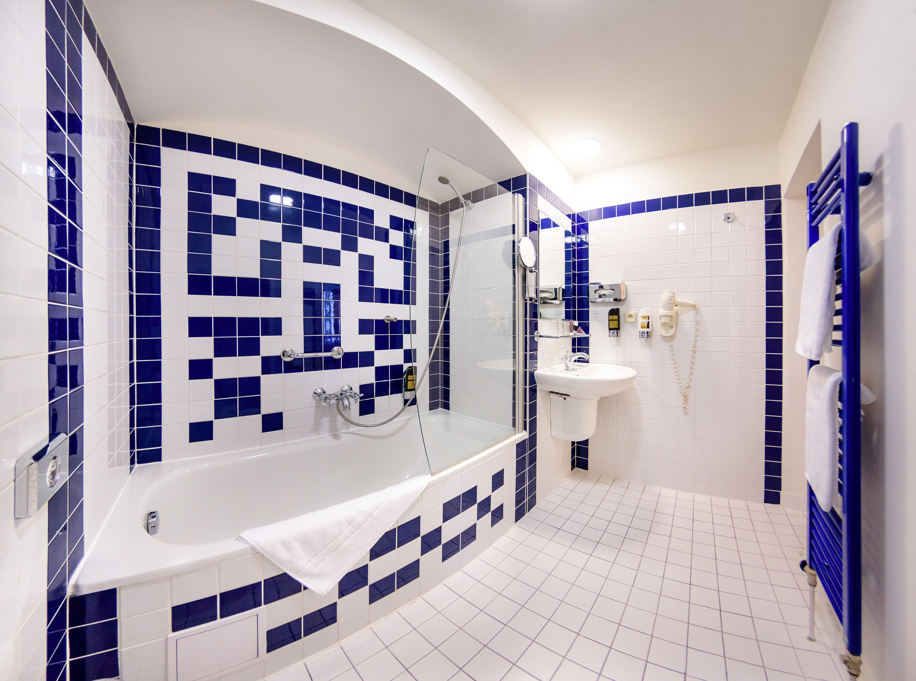 A bathroom with a bathtub, shower, and sink, featuring blue and white tiles.