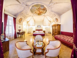 Um quarto espaçoso com uma cama grande, um guarda-roupa de madeira, uma mesa de jantar com cadeiras e um candelabro.