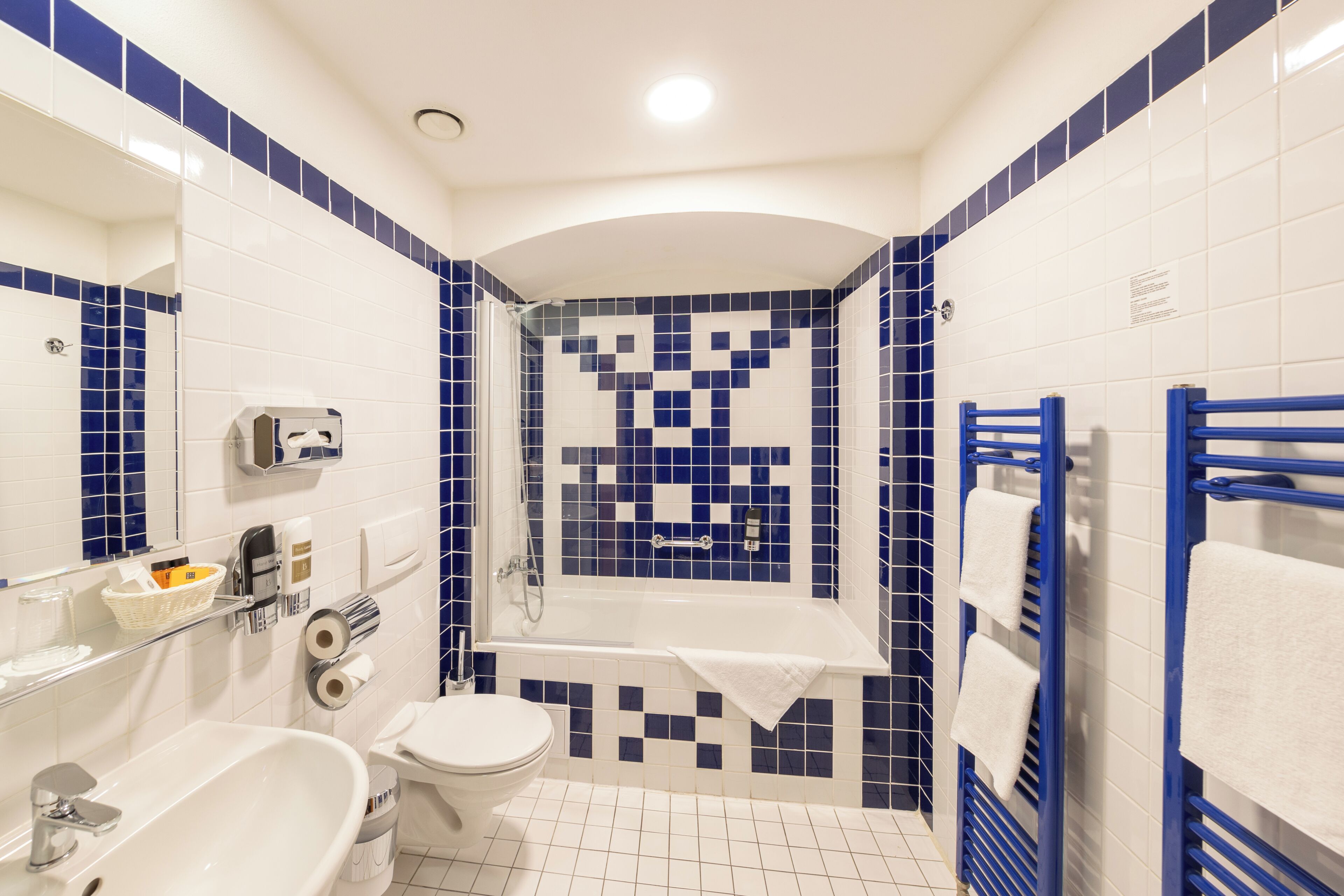 A bathroom with a bathtub, toilet, sink, and a mirror.