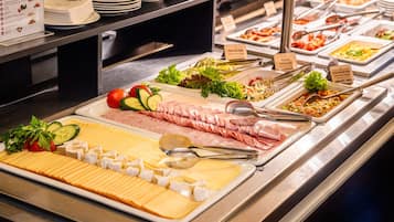 Un buffet con diverse portate, tra cui carni, formaggi e verdure.