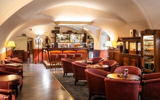 Uma área de bar com diversas opções de assento, um balcão e um refrigerador de vinhos.