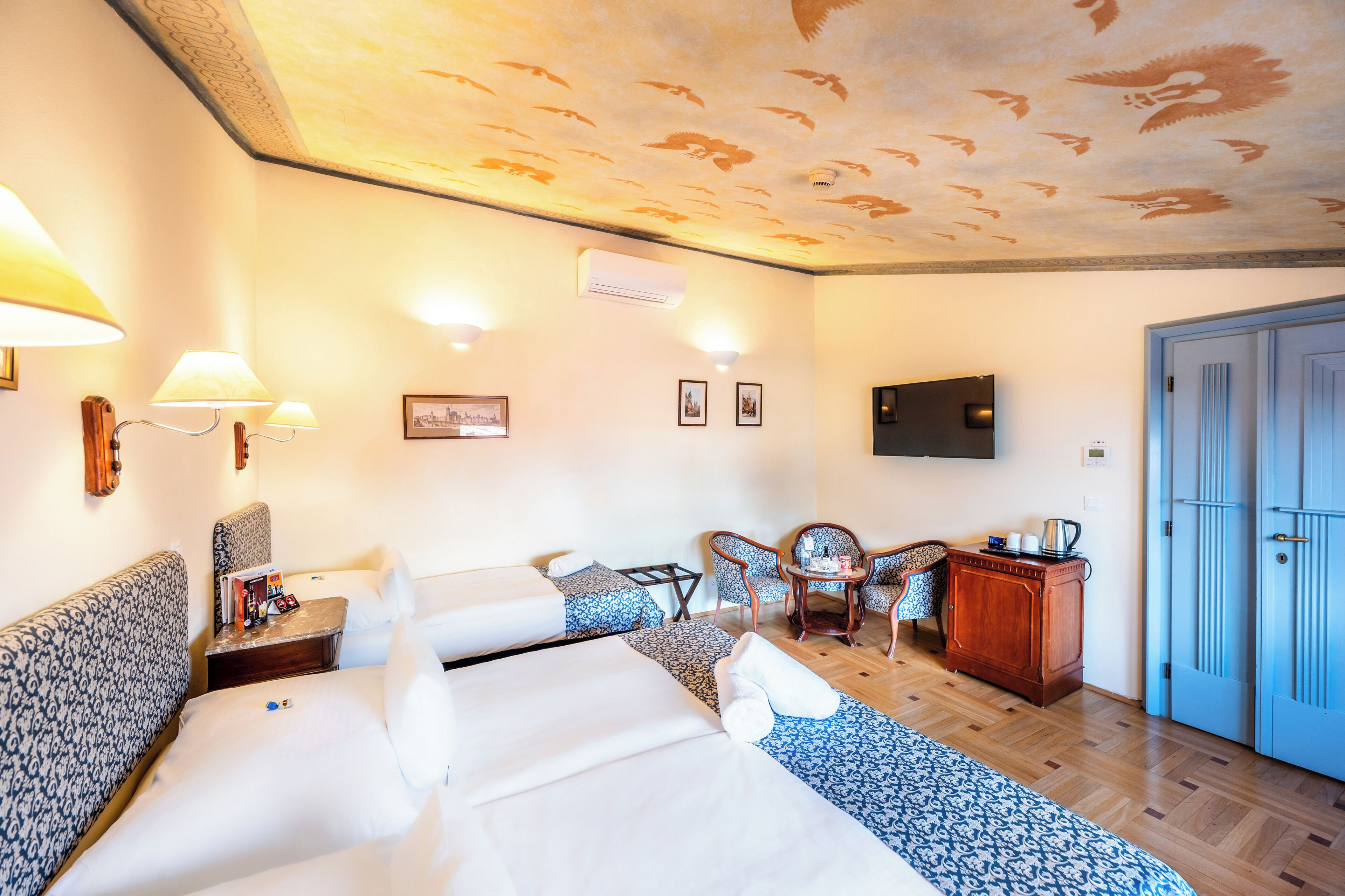 A hotel room with two beds, a TV, a desk with a chair, and a wardrobe.