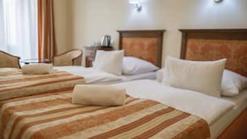 A hotel room with two beds, a nightstand, a lamp, and a window with curtains.