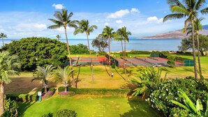 A tennis court with a view of the ocean and palm trees. - Maui Schooner Resort (Kihei)