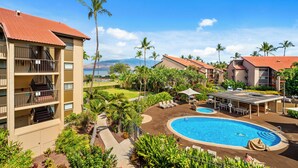 A hotel with a pool, outdoor seating, and a view of the ocean. - Maui Schooner Resort (Kihei)