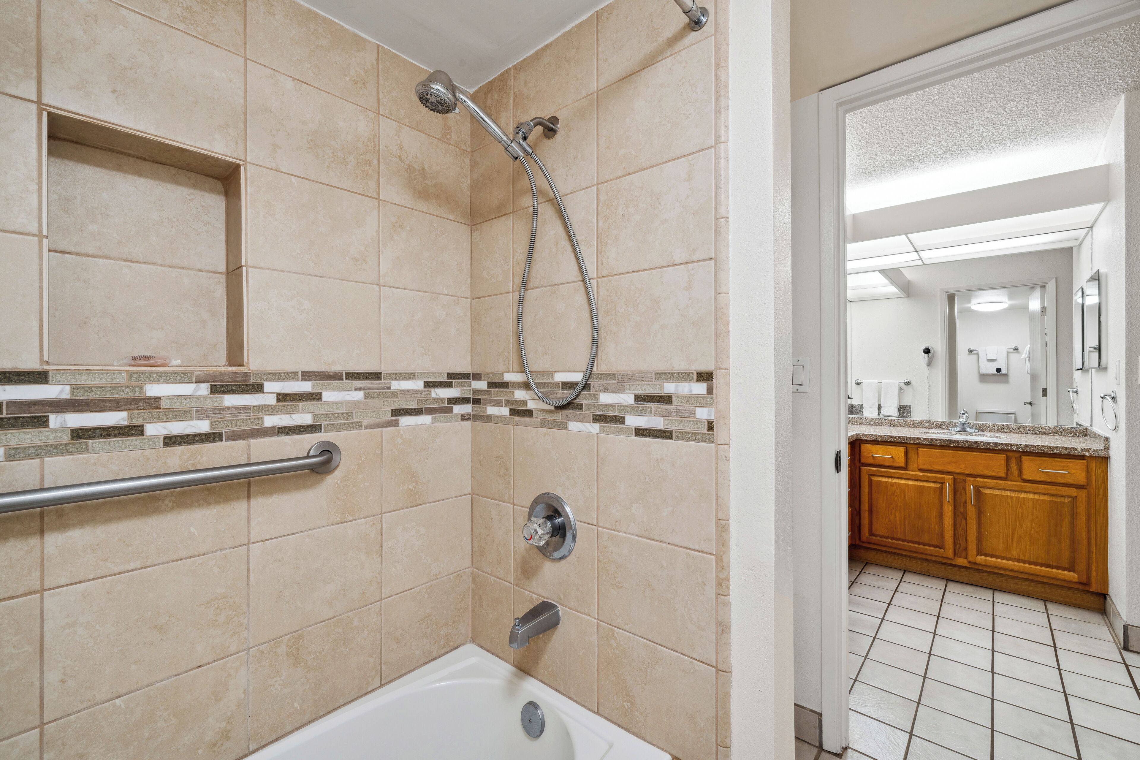 A bathroom with a shower, a bathtub, and a vanity with a mirror.