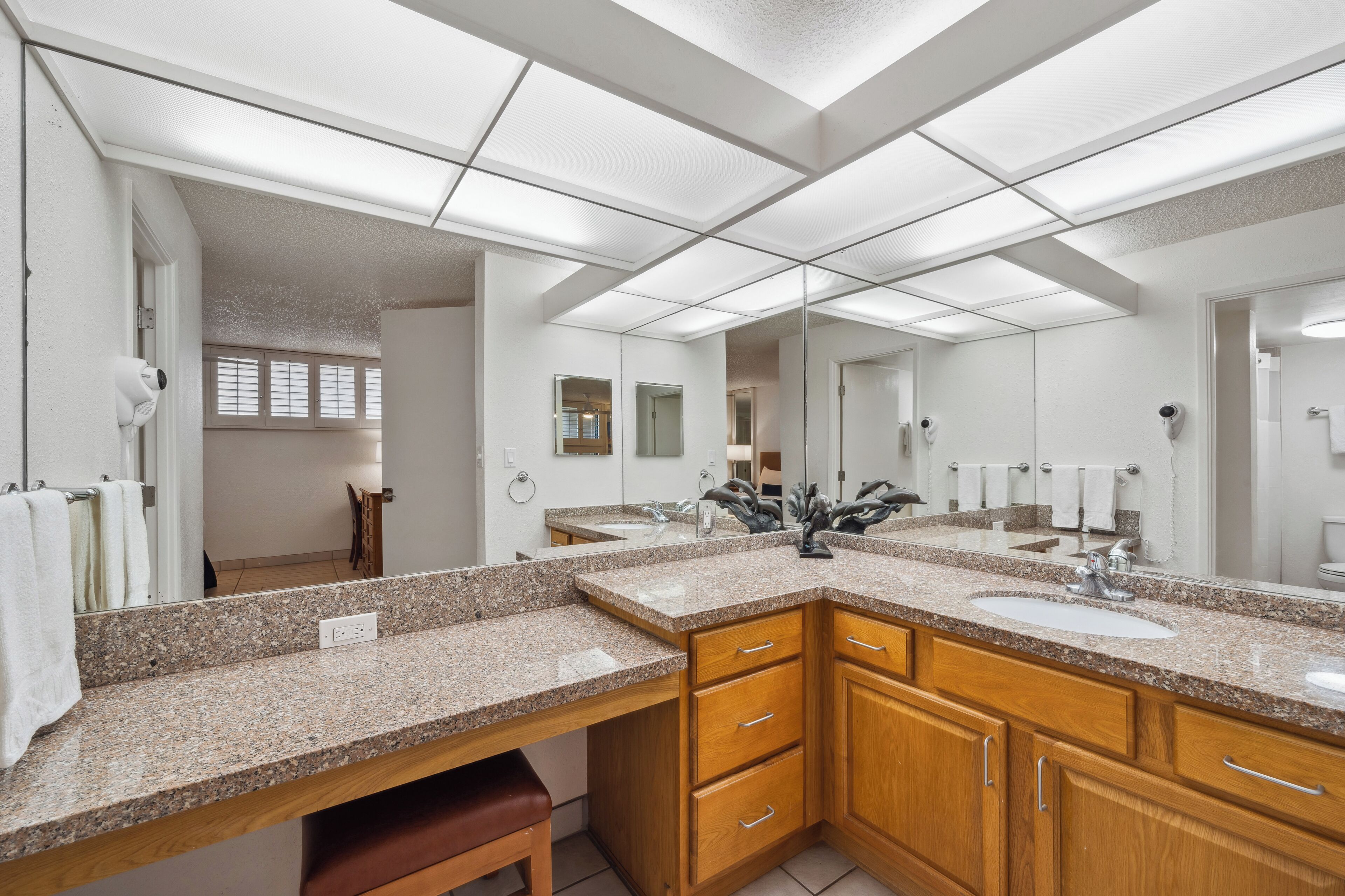 A modern bathroom with two sinks, wooden cabinets, and a large mirror.