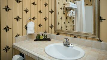 A bathroom with a sink, mirror, towel rack, and toilet paper dispenser.