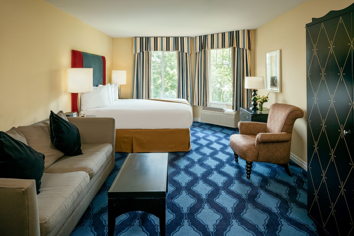 Een hotelkamer met een bed, een slaapbank, een stoel, een tafel en een kledingkast.