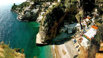 Un pueblo costero con edificios encaramados a acantilados, con vistas a aguas turquesas.